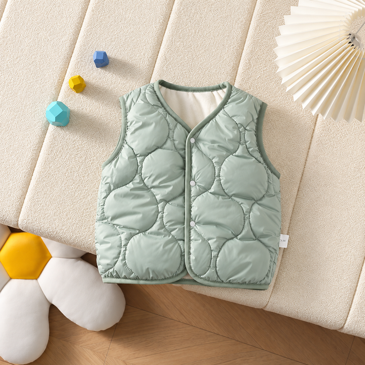 Sage green quilted baby vest with front snaps laid on a cream cushion.