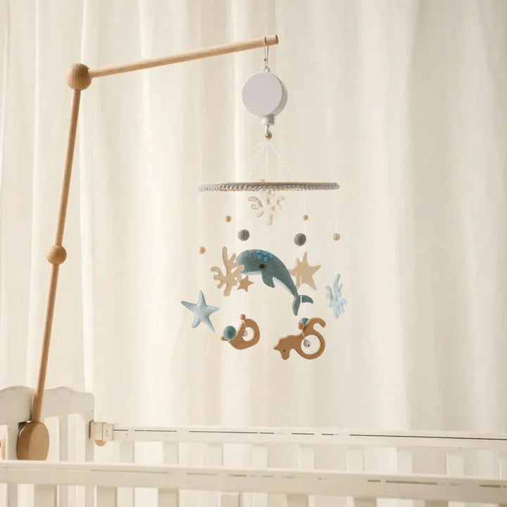 Seabed baby mobile suspended from a wooden mounting arm above a white crib