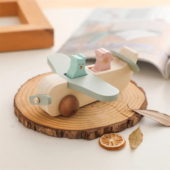 Wooden toy airplane with green wings and two animal passengers on a wood slice