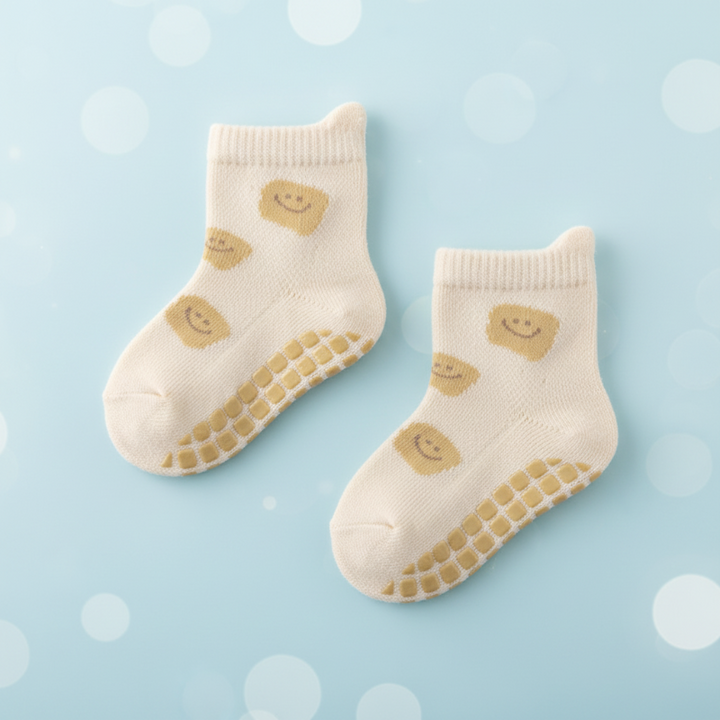 Cream baby socks with yellow smiley faces and matching yellow grip dots.