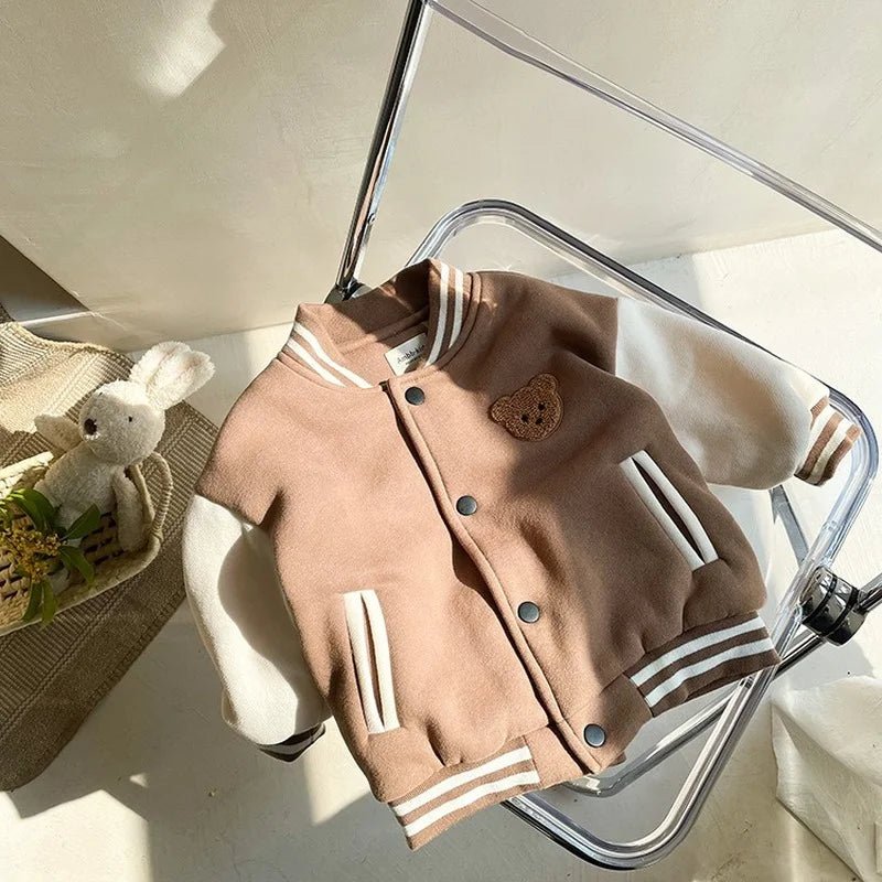 Brown and cream baseball jacket displayed on a chair with the snap front closed