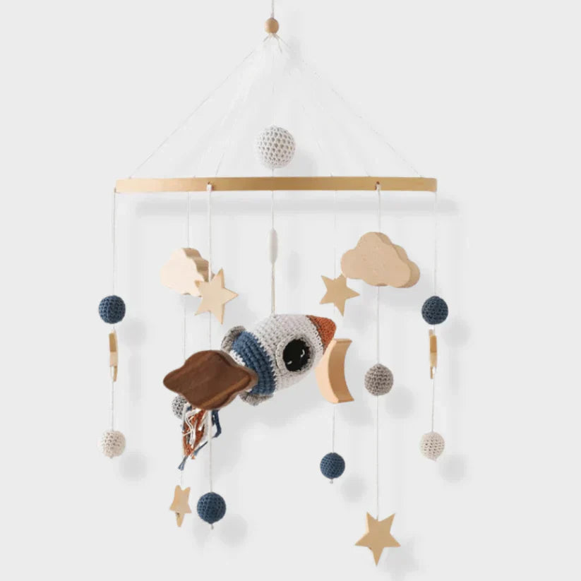 Space baby mobile with a textured rocket, wooden stars, a crescent moon, and clouds