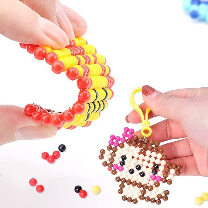 Hands bending a striped bead creation beside a monkey-shaped bead keychain