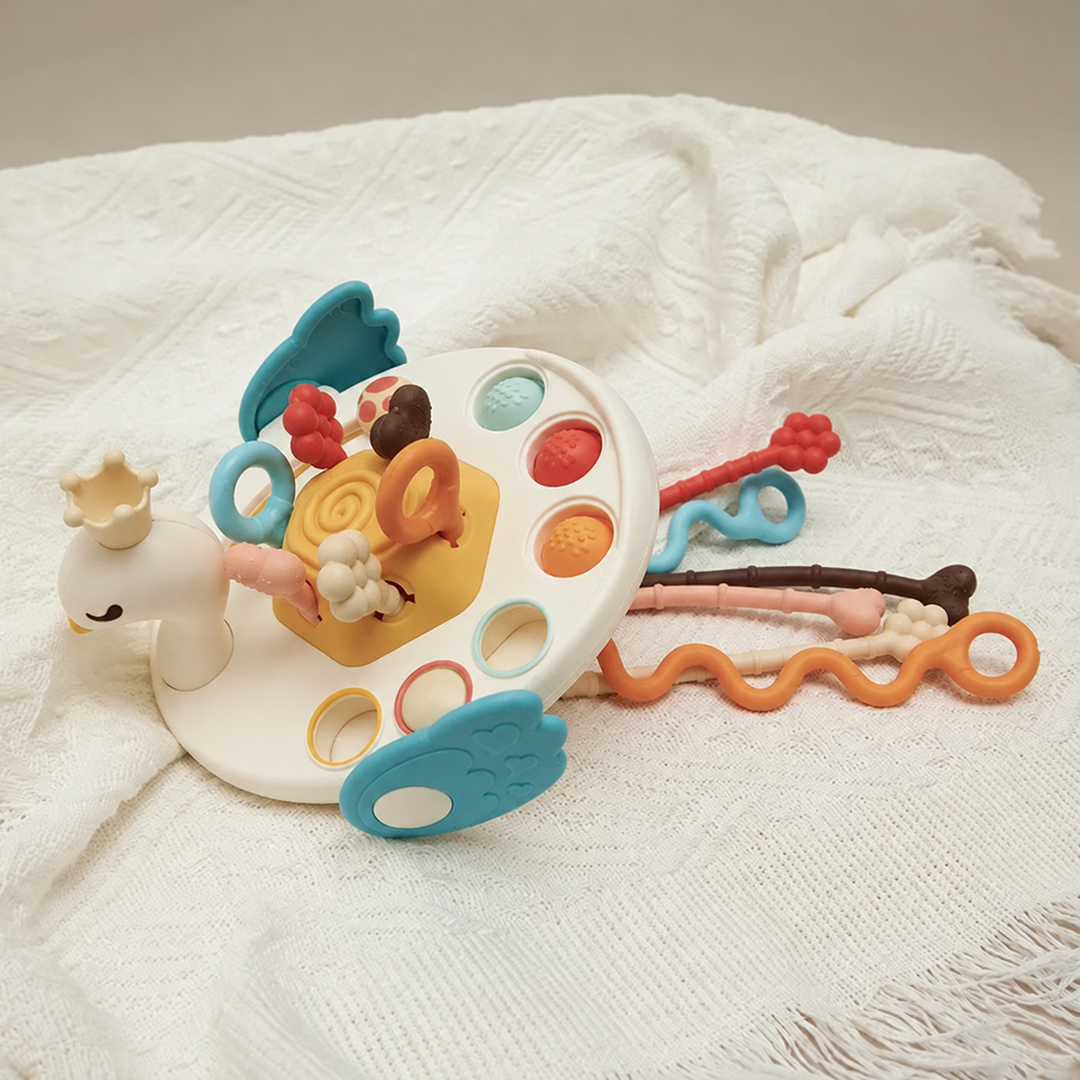 Swan-style sensory toy resting on a blanket with colorful cords extended