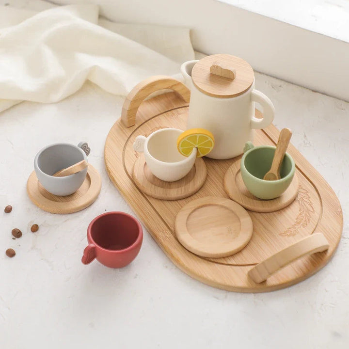 Tea set on a wooden serving tray with cups, saucers, a lidded pitcher, and a lemon-slice play piece