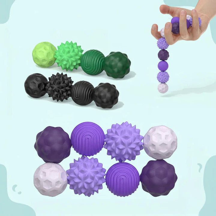 Textured magnetic silicone balls in green, black, purple, and white, with a hand holding a connected chain