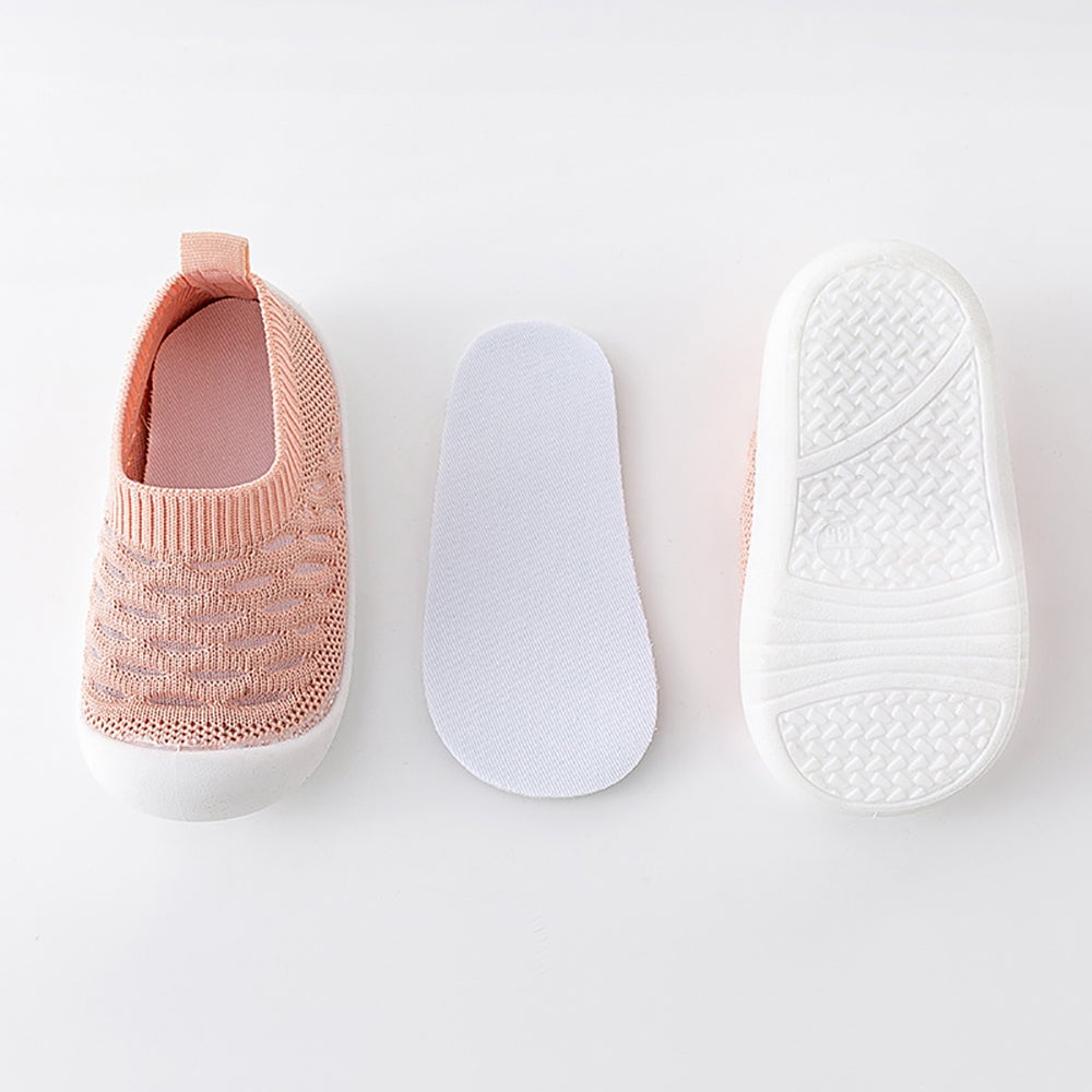 Pink knit shoe beside a white insole and textured white outsole