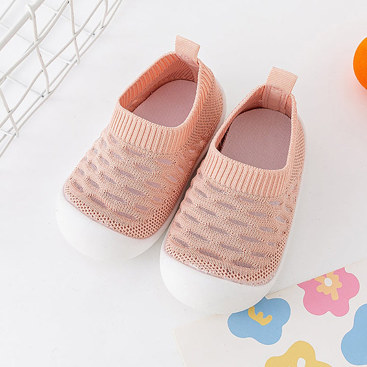 Pair of pink knit slip-on shoes with ribbed openings and white soles