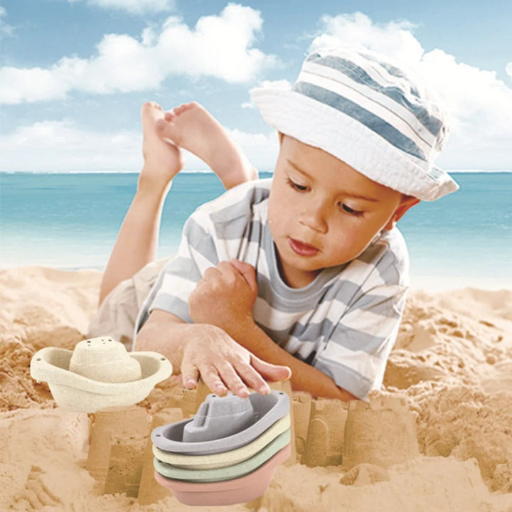 Child playing with pastel toy boats in the sand at the beach.