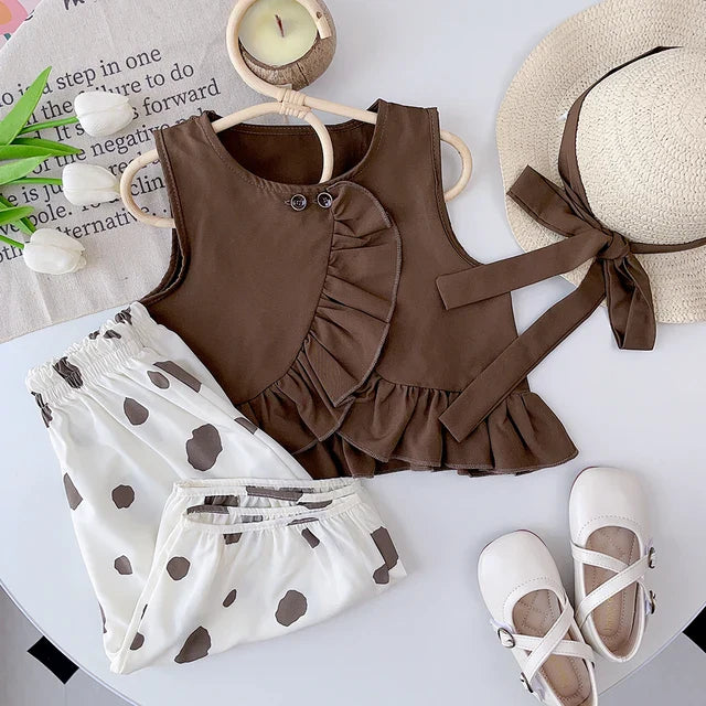 Brown ruffle top and dotted white bottoms displayed with a hat and white shoes