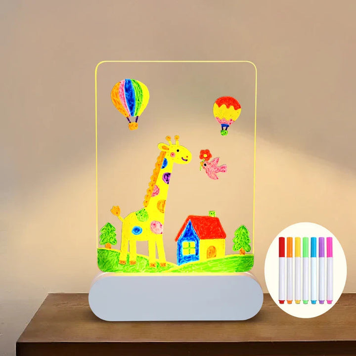 Giraffe and house artwork on a warm-lit drawing board with colored pens shown in an inset