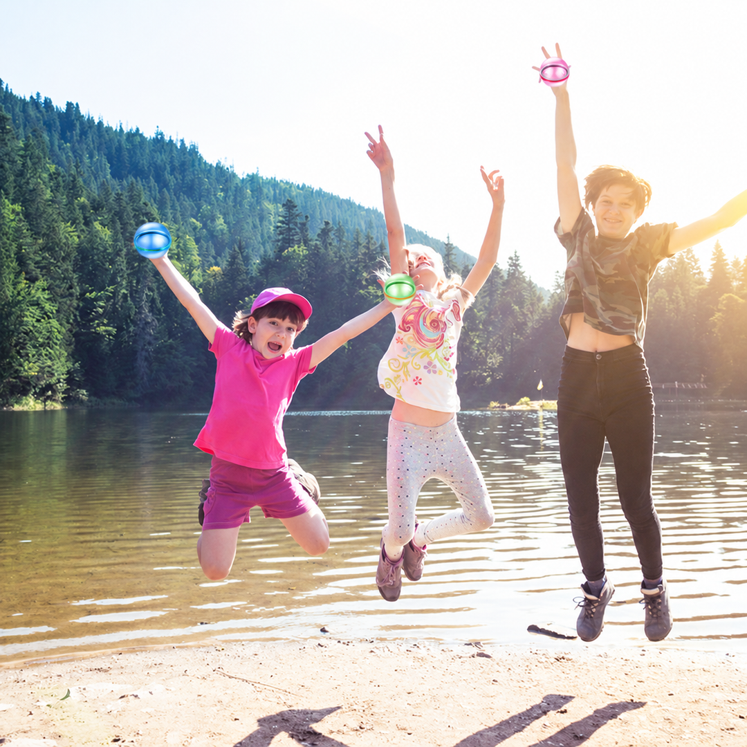Two children and an adult holding colorful water balloons beside a lake
