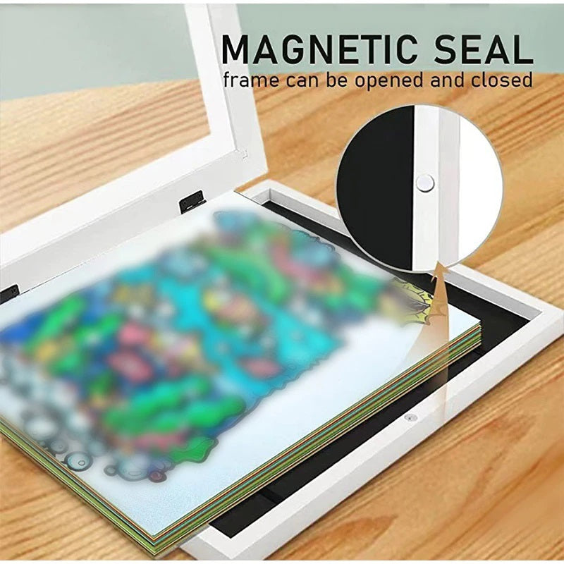 Open white art frame showing stacked drawings and a close-up of the magnetic closure