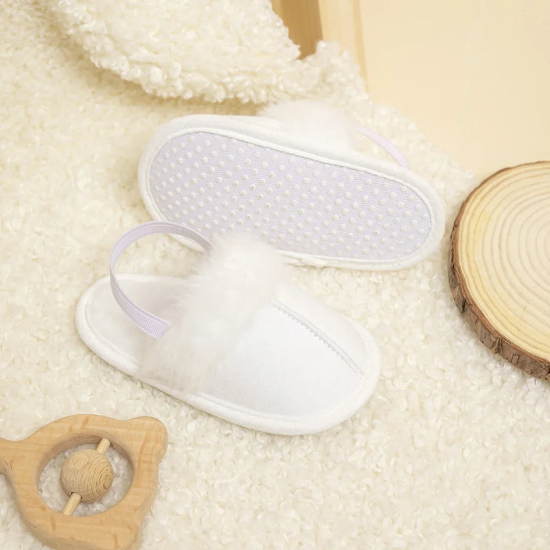 White baby slippers showing the plush upper and textured outsole
