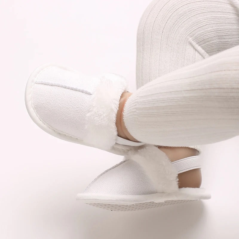 White baby slippers worn with cream ribbed leggings, showing the heel straps