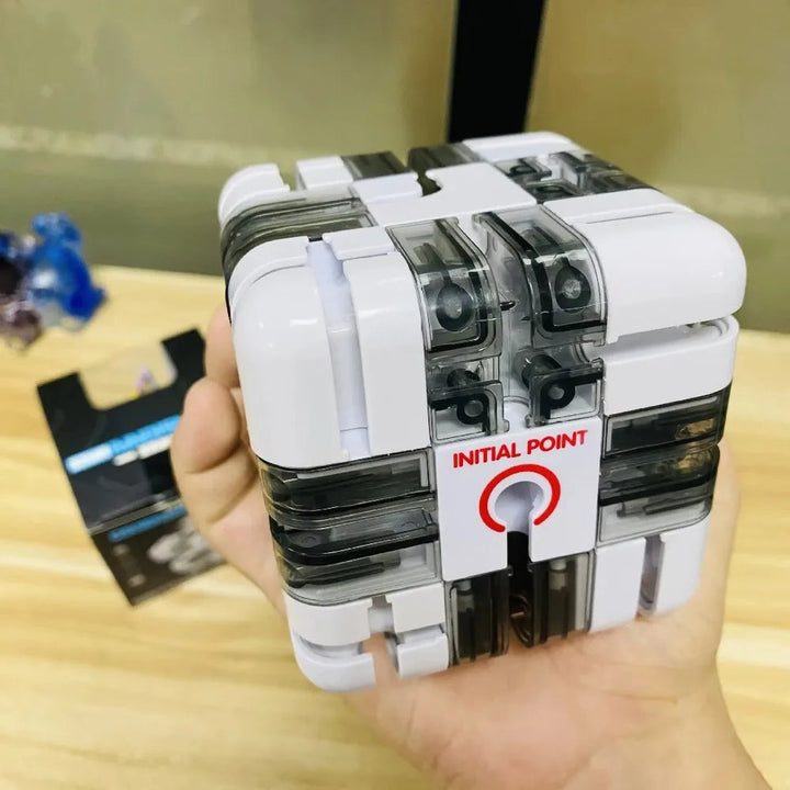 White ball-maze puzzle cube held in one hand with a marked starting point