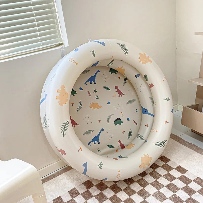 White round inflatable pool with colorful dinosaur and leaf prints on the sides and base.