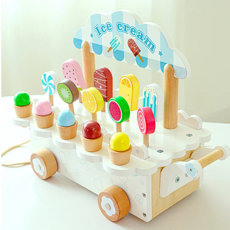 White wooden ice cream cart with a blue striped sign and colorful pretend treats on display