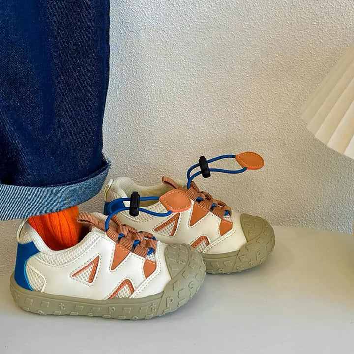 White color-block sneakers worn with orange socks and cuffed jeans