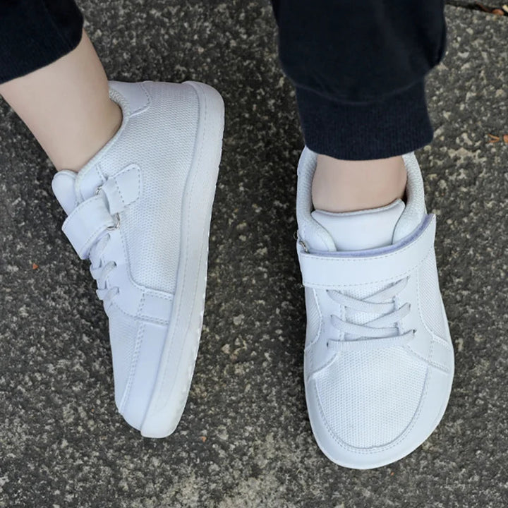 White mesh sneakers viewed from above while worn with black pants