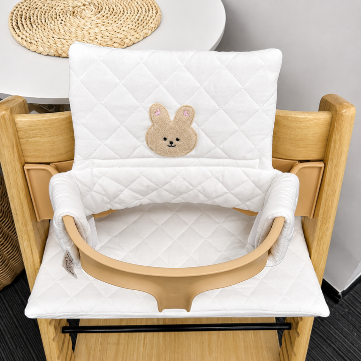 White quilted high chair cushion with a rabbit face patch on the backrest