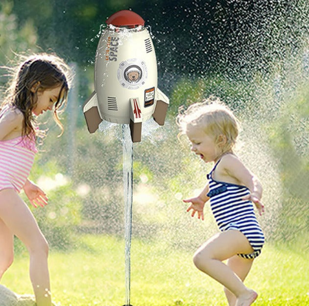 Children playing beside a white rocket sprinkler lifted by a water jet on a lawn