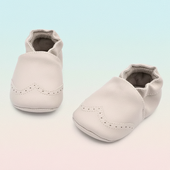 White baby shoes with rounded toes and decorative perforations