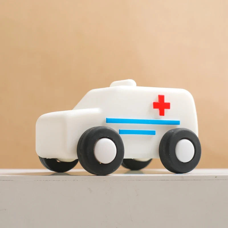 White silicone toy ambulance with a red cross, blue stripes and black wheels