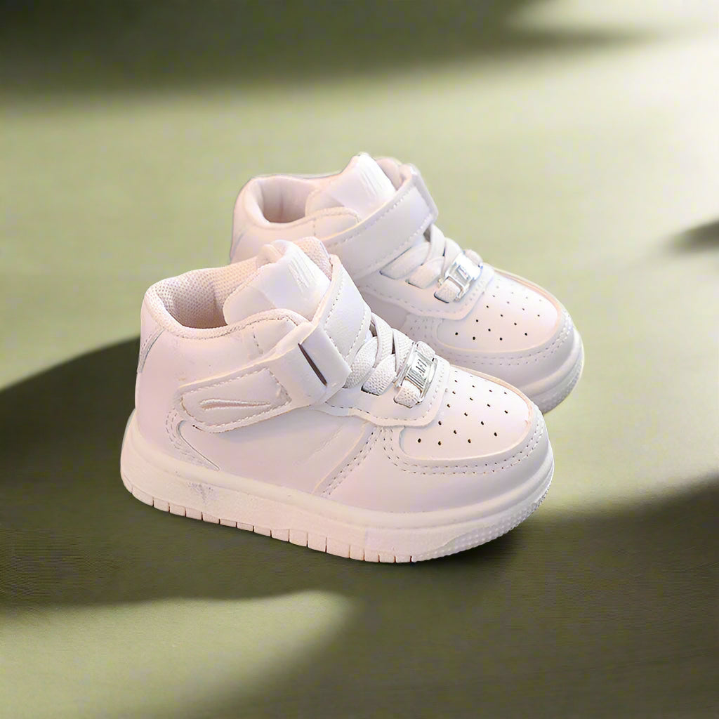 Pair of white high-top sneakers with hook-and-loop straps on a green bench