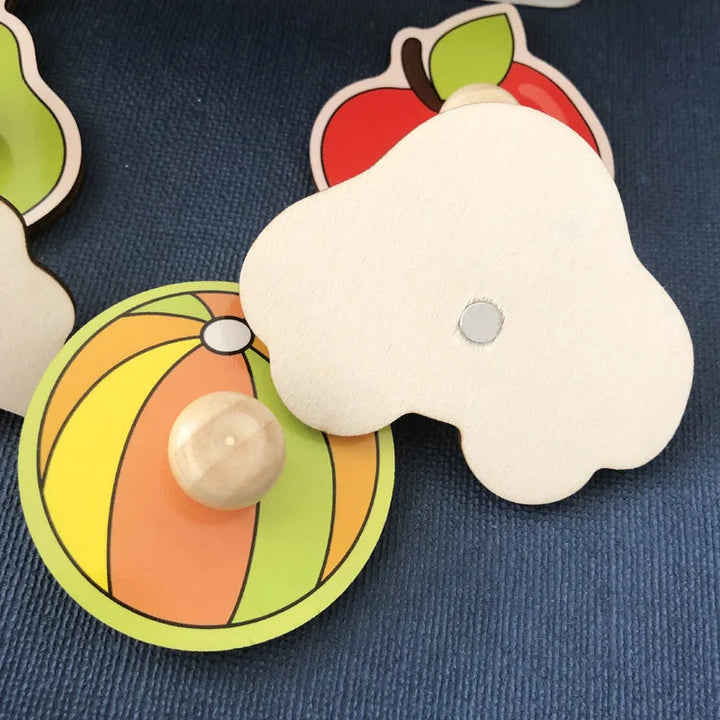 Underside of a wooden car puzzle piece beside colorful ball and apple pieces
