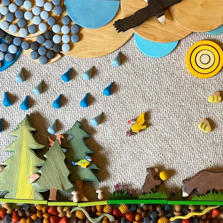 Wooden forest play scene with trees, animals and scattered blue loose parts