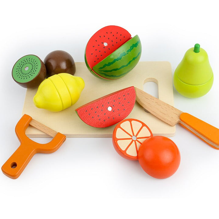 Wooden play fruits and slices with a cutting board, orange-handled knife and peeler