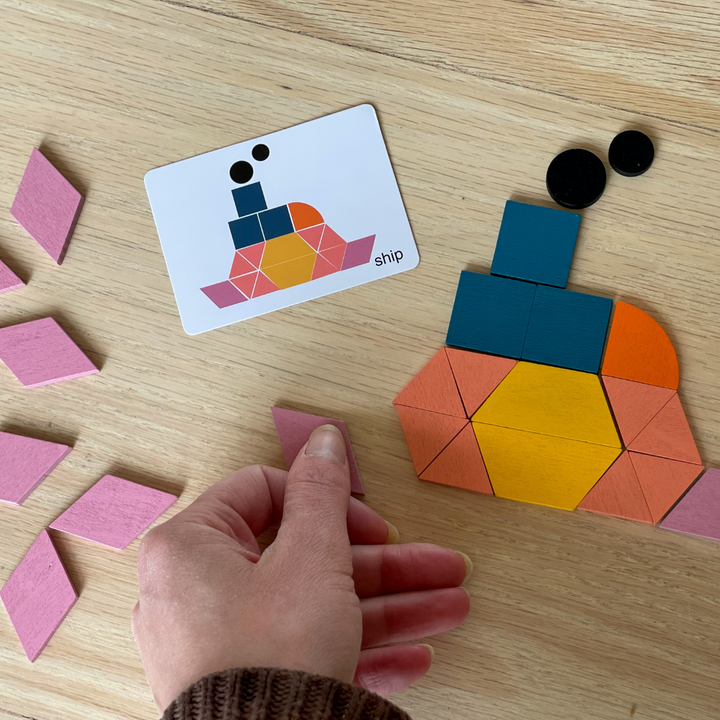 A hand assembling a colorful geometric design beside its matching pattern card