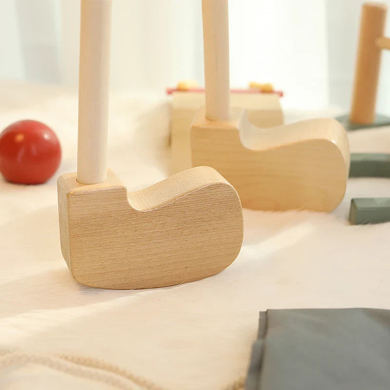 Close-up of two wooden golf club heads with a red ball and gray storage bag nearby