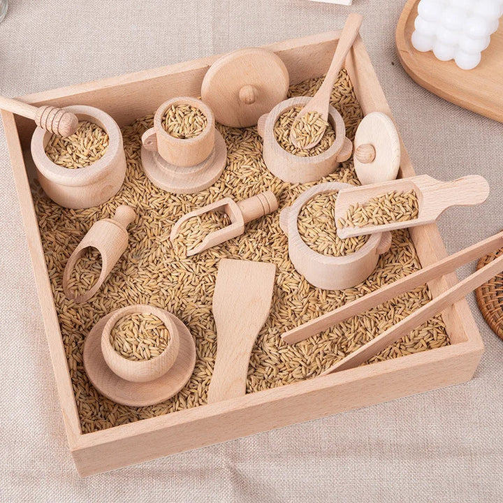 Wooden cups, pots, scoops and utensils arranged in a tray filled with grains.