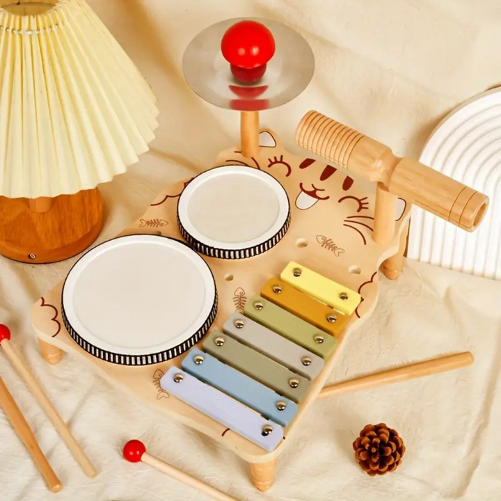 Wooden percussion set with drums, a xylophone, a cymbal, and loose sticks arranged on fabric