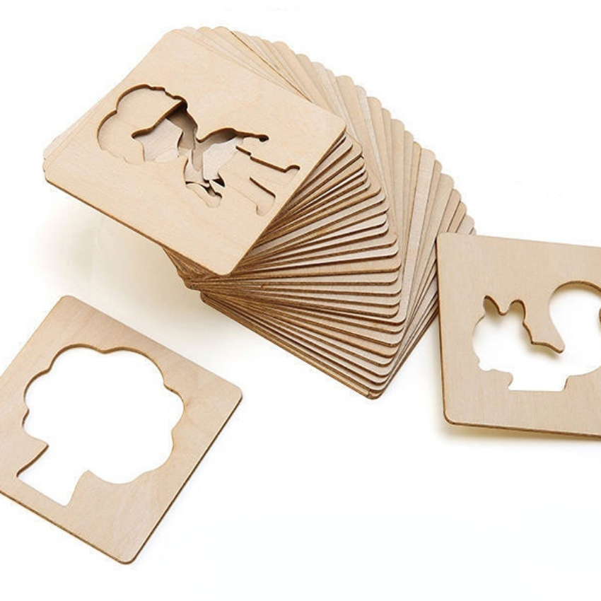 Stacked wooden drawing stencils with person and tree cutouts.