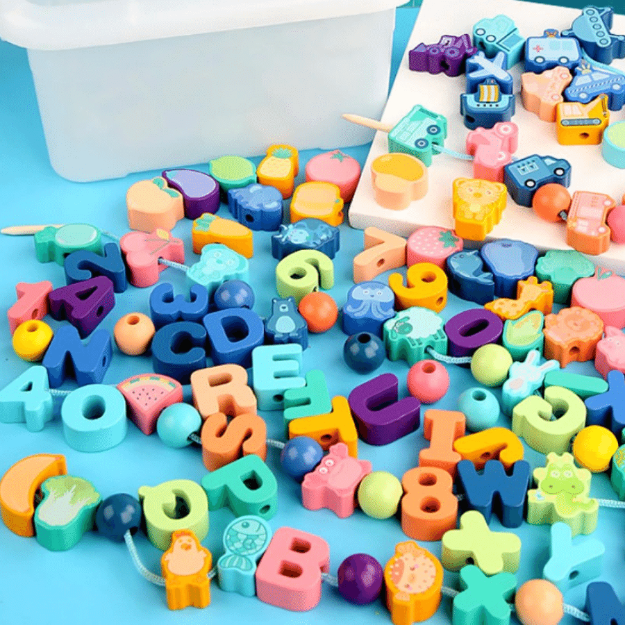 Colorful wooden letter, number, fruit, and vehicle beads beside a storage box
