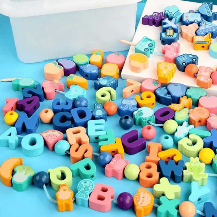 Colorful wooden letter, number, fruit, and vehicle beads beside a storage box