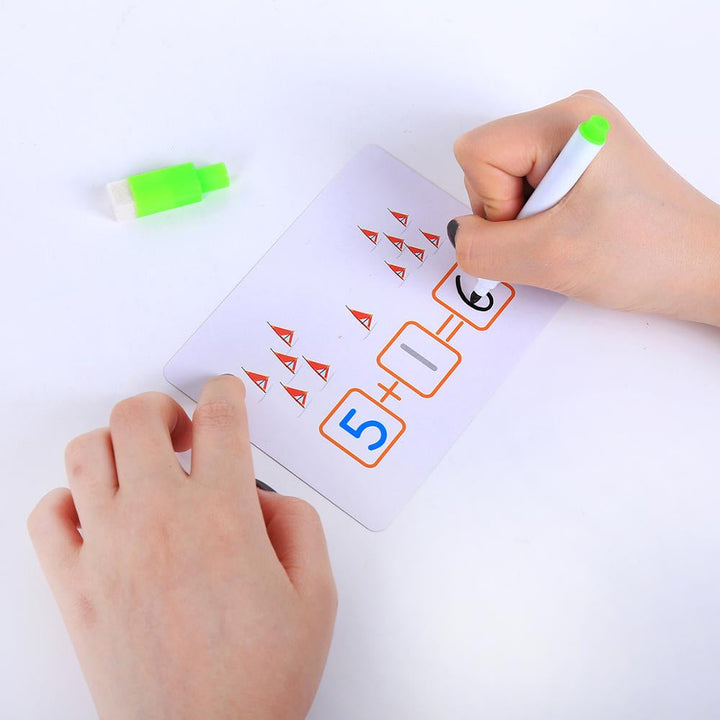 Hands writing an answer to 5 + 1 on an illustrated learning card