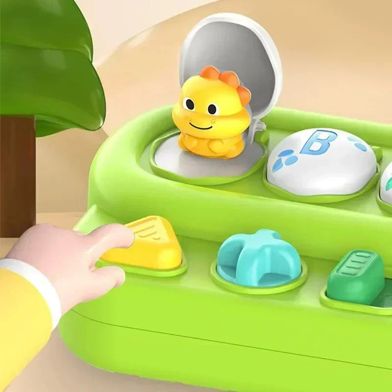 A hand presses the yellow control beside a raised yellow animal and a closed B lid