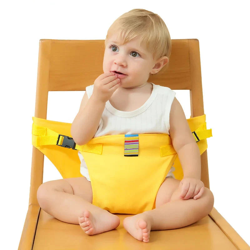 Child wearing a yellow baby chair harness while seated on a wooden dining chair.