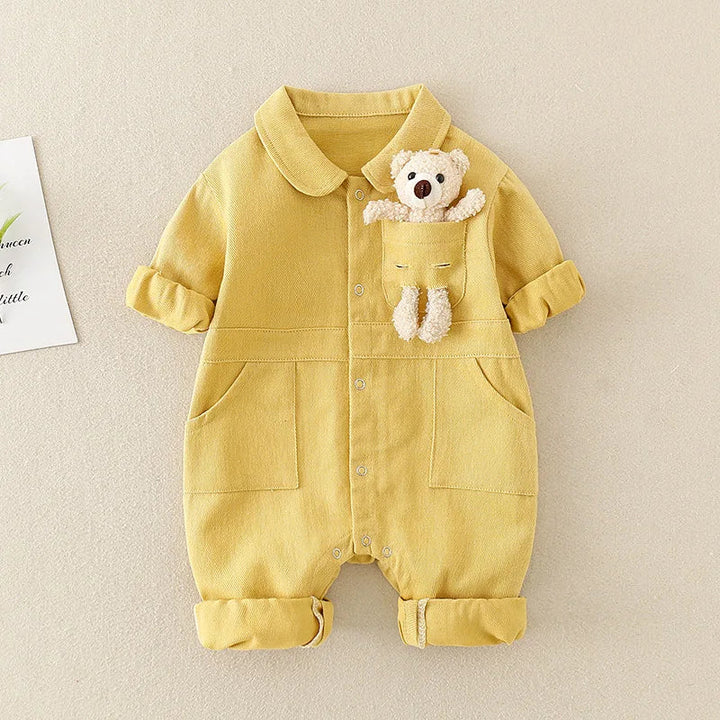 Yellow baby jumpsuit with a rounded collar, button front, rolled cuffs, and bear detail.