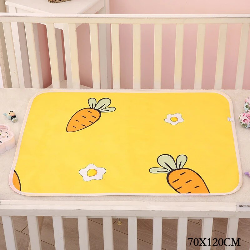 Yellow changing mat with large carrots and small flowers in a crib, labeled 70 x 120 cm.