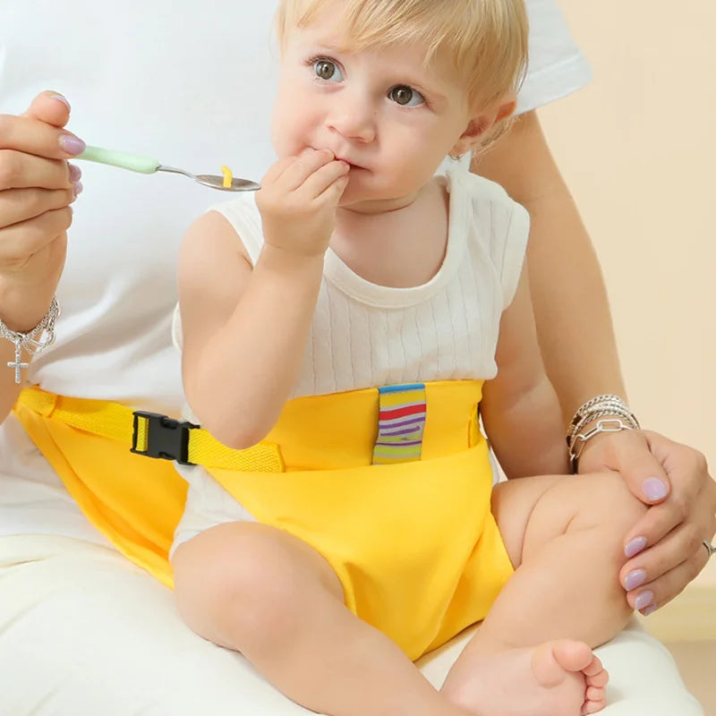 Child wearing the yellow harness while being spoon-fed on a caregiver&