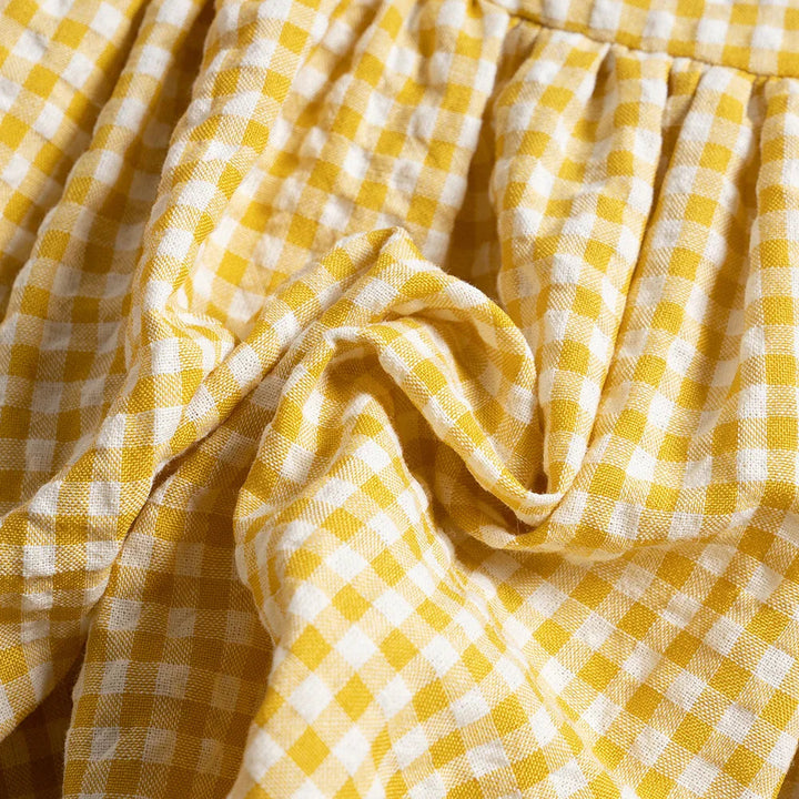 Close-up of yellow and white gingham cotton fabric gathered below the bodice