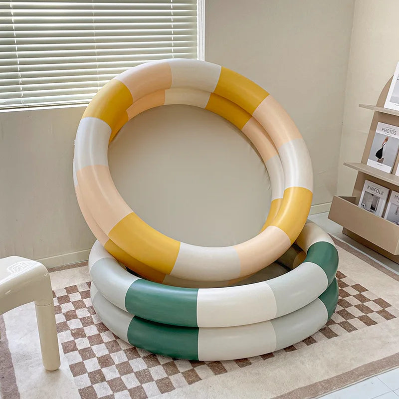 Yellow color-block inflatable pool propped above a green-and-white pool indoors.