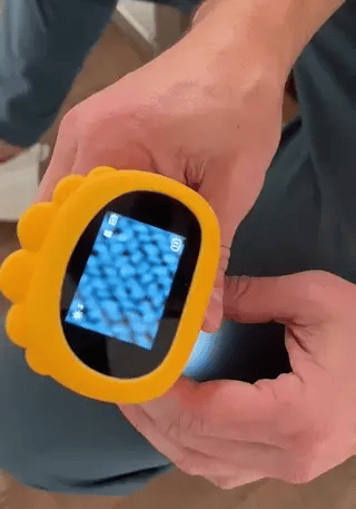 Yellow handheld microscope showing a magnified view on its color screen.