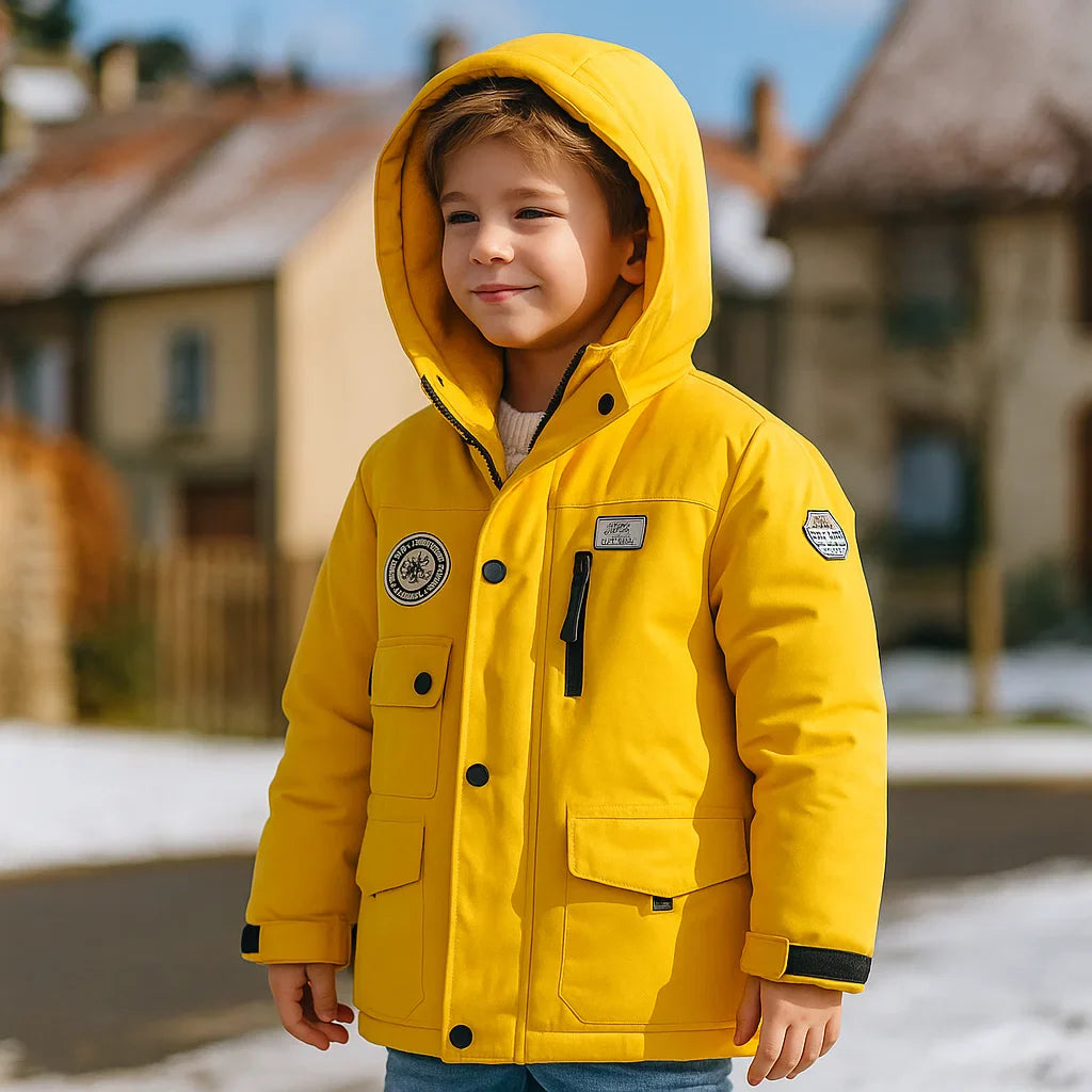 Child wearing a yellow hooded ski jacket outdoors near snow