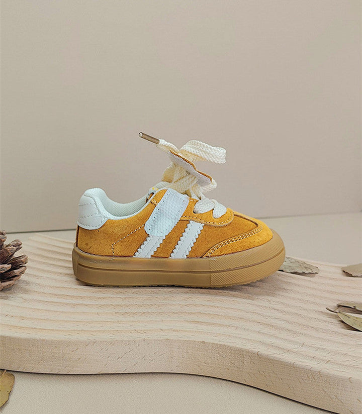 Side view of a yellow lace-up sneaker with white stripes and a gum-colored sole